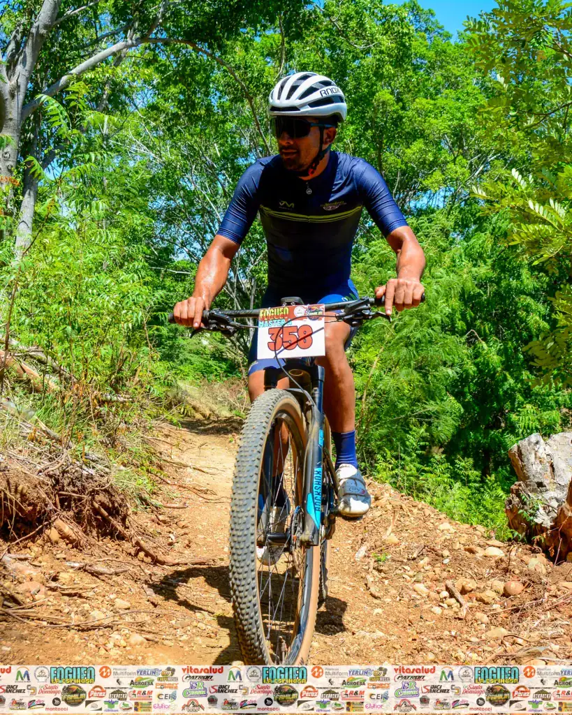 Denny Lopez montando bicicleta de montaña en sendero natural.