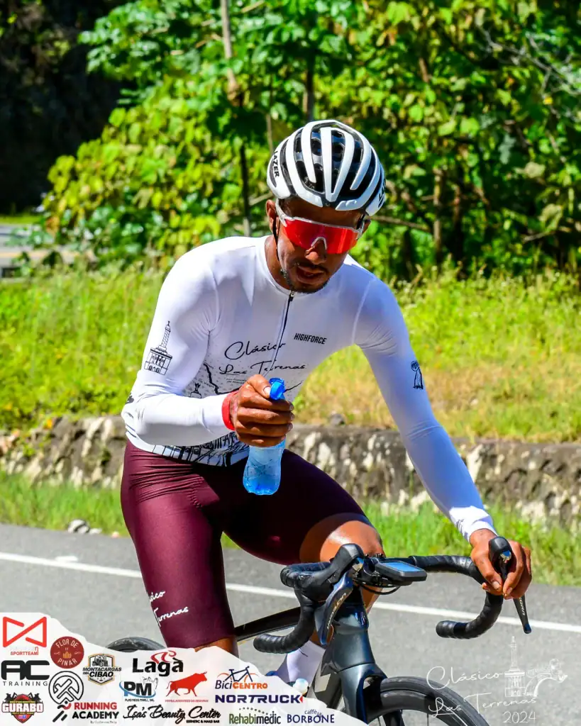 Entrenador de ciclismo en acción, usando casco y ropa deportiva, en un entorno natural.