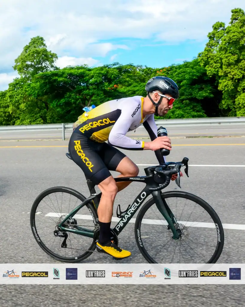 Ciclista en ruta con equipo profesional en bicicleta de carrera, usando casco y ropa deportiva, en u.