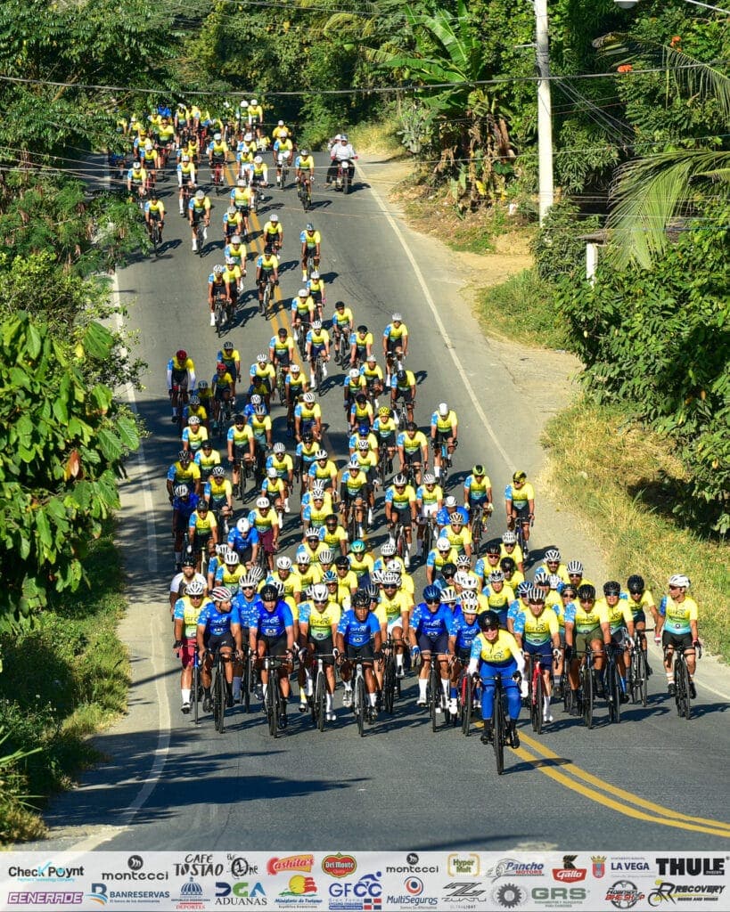 Ciclistas participando en una ruta en bicicleta en un paisaje rodeado de vegetación y árboles.