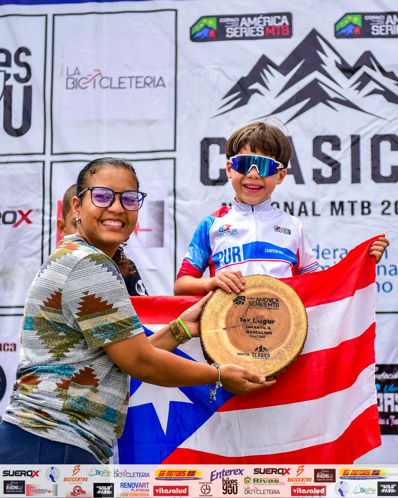 Niño y mujer con trofeo y bandera de Costa Rica en competencia de MTB.