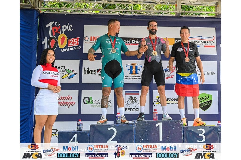 Podio de ciclismo con ganadores en el podio y medallas en evento deportivo.